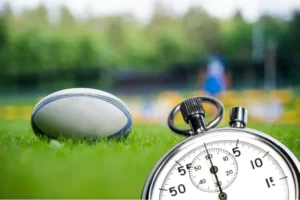 un ballon de rugby au sol et un chronomètre en premier plan