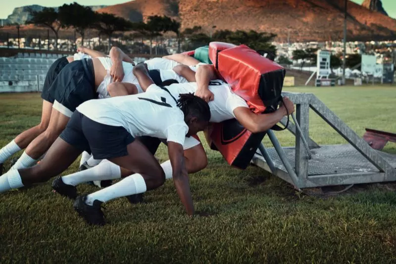 Des rugbymen en plein entrainement avec un simulateur de mêlée